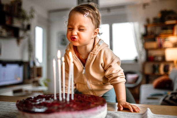 petite fille d’anniversaire soufflant des bougies sur un gâteau à la maison - anniversaire photos et images de collection