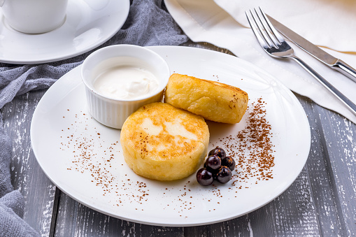 cheesecakes from cottage cheese with sour cream on white plate