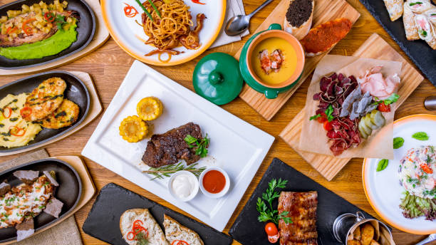 istock roast beef Steak with corn, pea soup, sliced meat, bbq pork ribs, chicken pattys with mashed potatoes top view on wooden table 1393199153