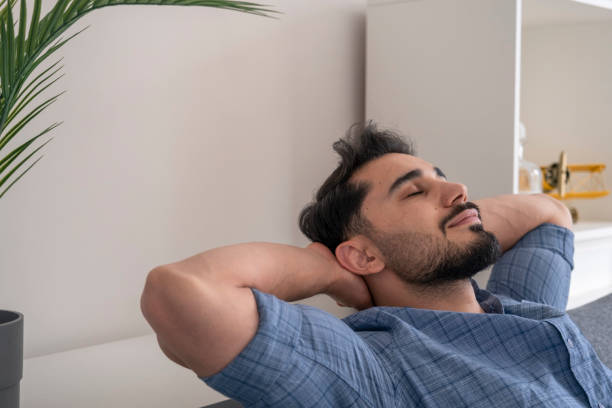 Peaceful young man  resting on sofa with closed eyes stock photo