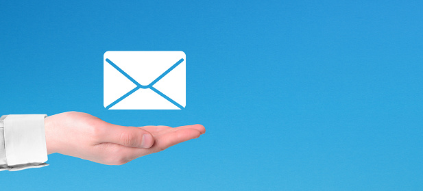 Hand holding email icon with copy space on blue background. Email marketing and newsletter