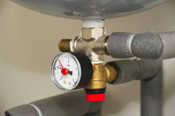 Pressure gauge on domestic boiler expansion vessel inside house UK