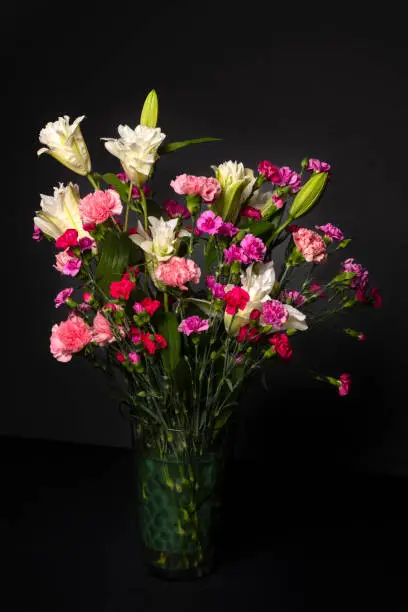 Colorful flower bouquet arrangement in vase isolated on black.