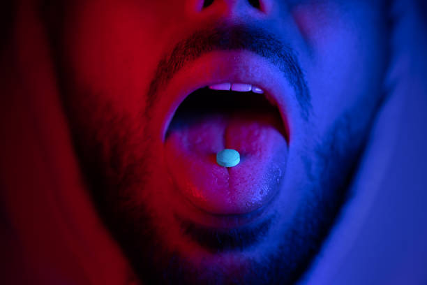 primo piano della bocca dell'uomo che ingoia droghe ecstasy. uomo che prende la pillola di ecstasy mdma. - narcotic foto e immagini stock