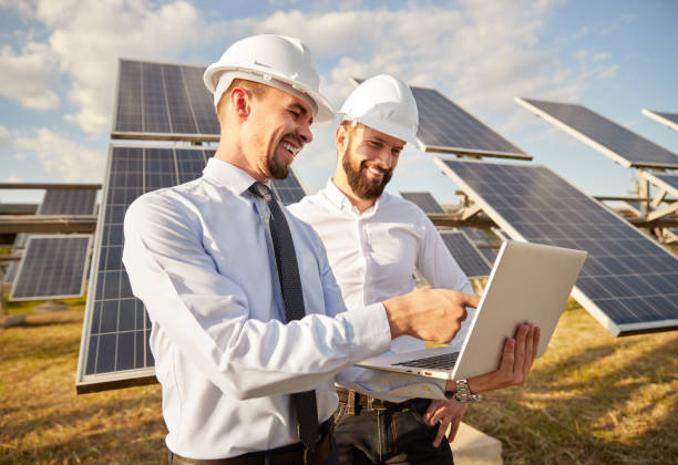 Engineer using laptop near photovoltaic panels producing renewable solar energy stock photo