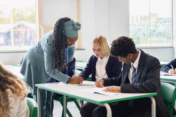 istock Mature female educator helping secondary students in class 1393223789