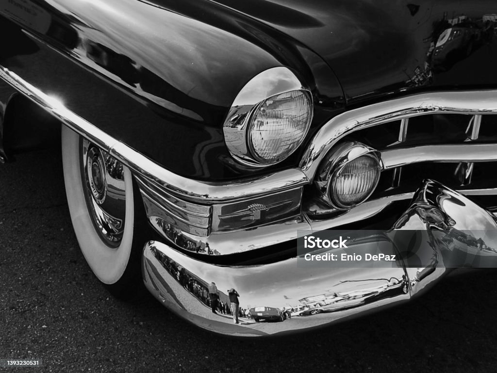 Car Headlight on Old Car Black and white photograph.  Car headlight on black old car with chrome bumper.  White wall tires.  Rounded fenders and rounded bumpers. Vintage Car Stock Photo