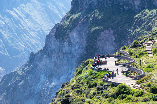 Cruz Del Condor, Colca Canyon, Peru - April 18, 2022; Cruz del Condor is a popular tourist stop to view the Andean condor. At this point the canyon floor is 1,200 metres (3,900 ft) below the rim of the canyon. This place was originally called Chacllacruz yet it is now known by the title of “Cruz del Condor” (Condor’s Cross) for two reasons: one, for the flyovers performed in this area by this famous Andean bird, especially in the morning, and two, because of the stone cross built overtop a striking stone promontory.