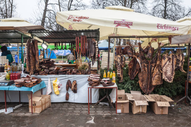 киоск мясника на рынке slaninijada kacarevo, продающий копченое и вяленое мясо, а также сушеную свинину, также называемую suvo meso на сербском языке. - market market stall shopping people стоковые фото и изображения