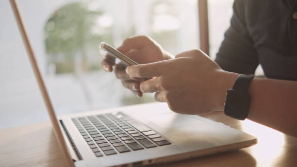 istock The hand wearing a smart watch is tapping the smartphone screen and using a laptop computer. 1393244775