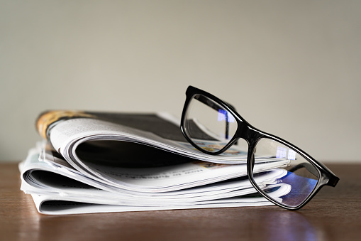 Blue light blocking glasses on stack of Newspapers