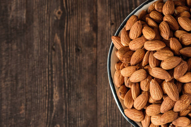 istock Almonds in wood bowl on wood table.Diet raw material 1393251357
