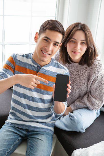 istock Teenager sibling pointing at iphone 1393254613