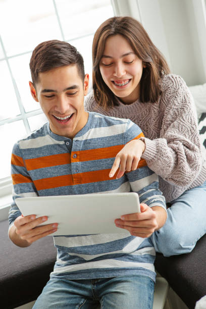istock Ecstatic teenage sibling using tablet at home 1393254852