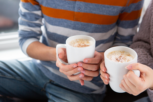 Sibling hands holding hot chocolate latte drink up close.