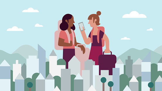 Two Girlfriends Look at Mobile Phone While Traveling in Cityscape Together