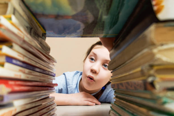 mädchen untersucht mit interesse und neugier stapel von büchern, die auf dem lesen liegen, bücher - childrens literature stock-fotos und bilder