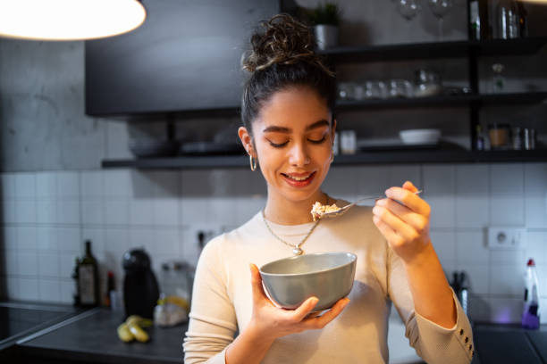 eine junge frau isst haferflocken - oatmeal stock-fotos und bilder