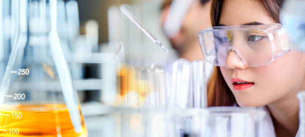 Attractive scientist woman looking chemical sample in flask at laboratory stock photo