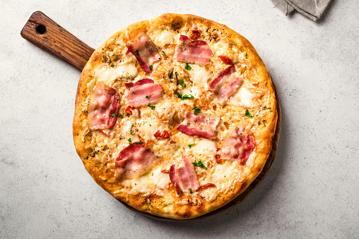 Bacon Pizza. Italian Carbonara Pizza with bacon and mozzarella cheese on white table, top view, close up.