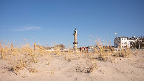 Warnemünde, Rostock, Germany - March 3, 2022: View of the lighthouse in Warnemünde Rostock over a dune near the Baltic Sea in the Baltic Sea resort.