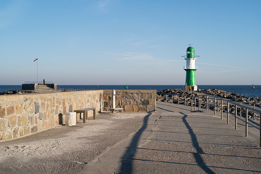 Warnemünde, Rostock, Germany - March 3, 2022: At the pier with the lighthouse west pier and pier light in Warnemünde in the early morning. View of the Baltic Sea with horizon.