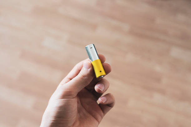 istock hand holding the charged electric alkaline aa battery 1393270896