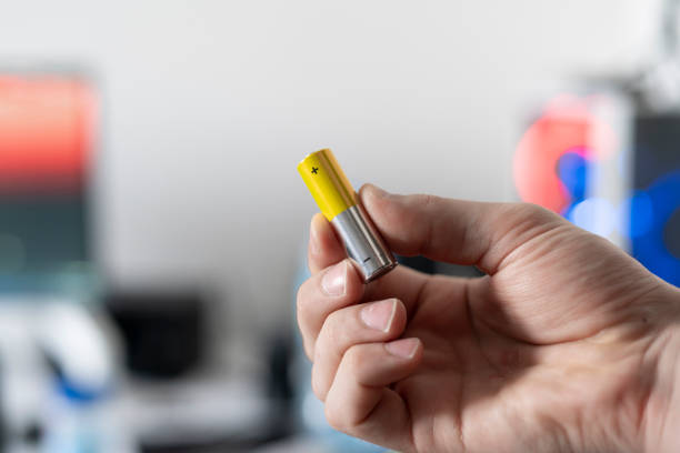 istock hand holding the charged electric alkaline aa battery 1393270897