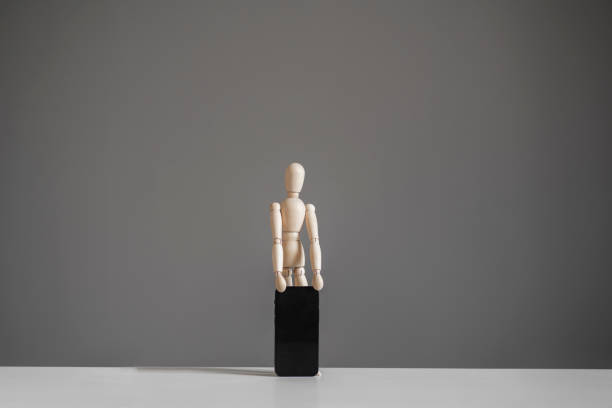 small wooden figure holds new smartphone, mobile technology