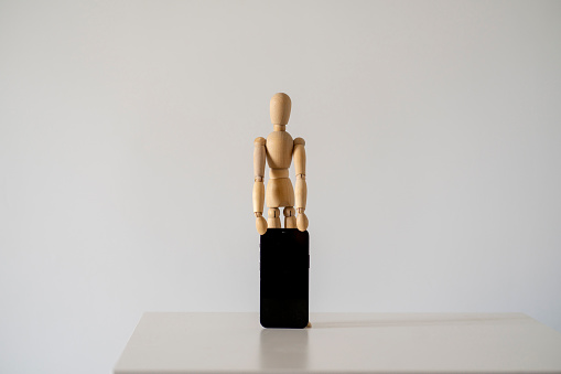 small wooden figure holds new smartphone, mobile technology