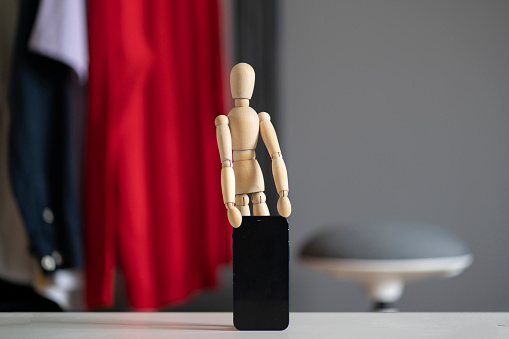 small wooden figure holds new smartphone, mobile technology
