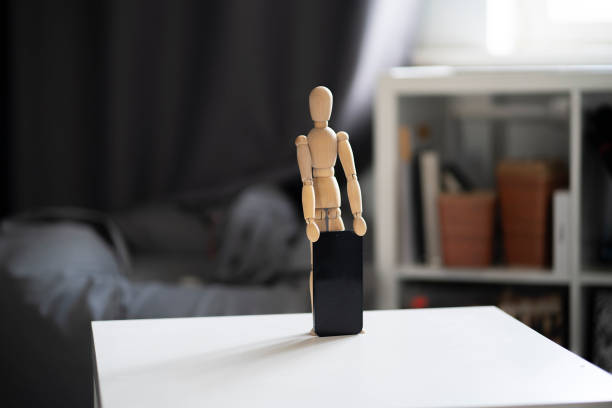 small wooden figure holds new smartphone, mobile technology