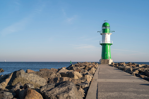 Warnemünde, Rostock, Germany - March 3, 2022: At the pier with the lighthouse west pier and pier light in Warnemünde in the early morning. View of the Baltic Sea with horizon.
