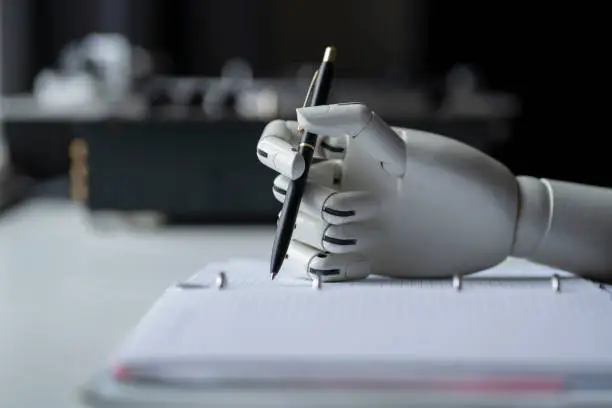 Photo of artificial robotic arm write down some notes with pen