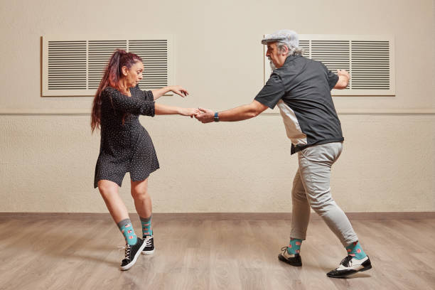 Dance couple doing a lindy hop dance move Mature couple dancing Lindy Hop in a ballroom practicing dance moves to keep fit lindy hop stock pictures, royalty-free photos & images
