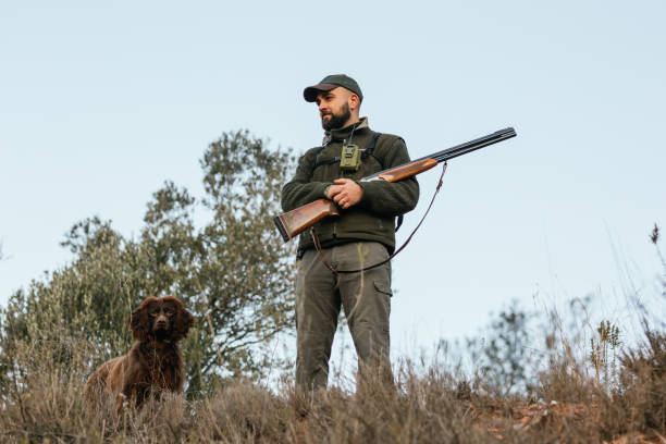 istock Hunter man standing looking away with his dog in mountain 1393276823