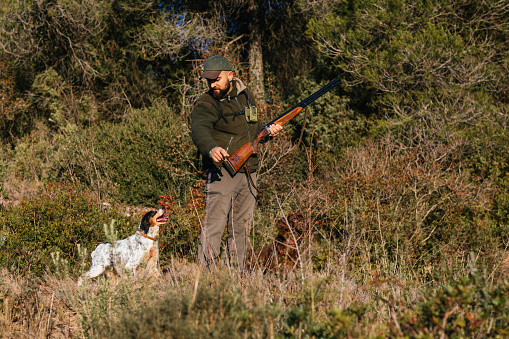 Male hunter hunting with his hunting dog outdoors. Hunting season concept.