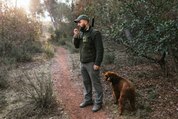 istock Hunter talking on walkie talkie in forest with purebred dog 1393276855
