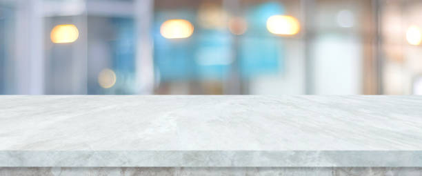 istock Empty white table top, counter, desk over blur perspective store with bokeh light background, White marble stone table, shelf and blurred shop for food, product display mockup, template backdrop, banner, Retail business wallpaper, poster 1393280240
