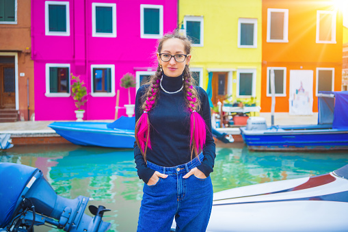 Happy traveler woman having fun near colorful houses on Burano island in Venetian lagoon. Travel and vacation in Italy concept. Lifestyle travel moments in the beautiful italian city.