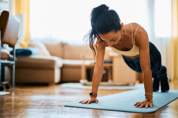 istock Female athlete practicing push-up while working out in the living rom. 1393283893