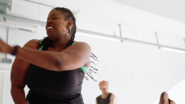 Fit plus size woman doing zumba dance in fitness class