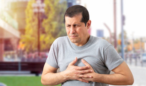 Chest pains are never a good sign Shot of a man holding his chest in discomfort due to pain in the street during the day.Heart attack concept. male chest pain stock pictures, royalty-free photos & images