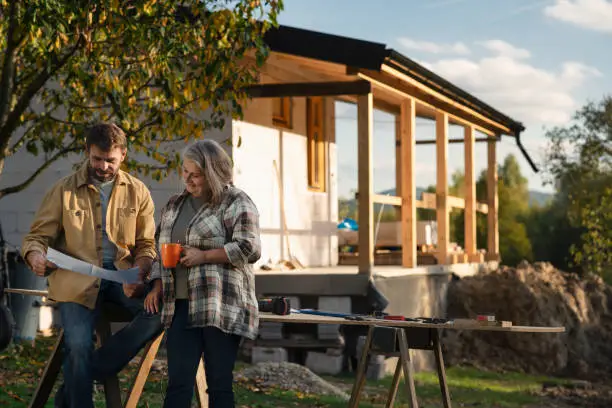 Photo of Mature couple having coffee break when working together on construction site of their new house.