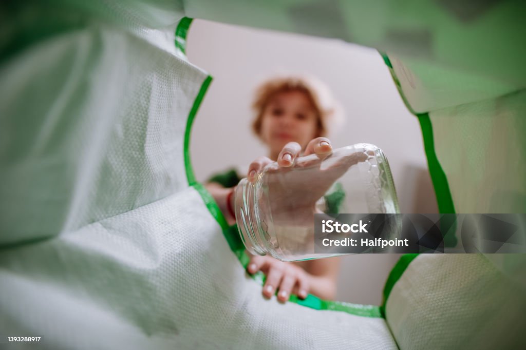 Image from inside green recycling bag of girl throwing a glass bottle to recycle. An image from inside green recycling bag of girl throwing a glass bottle to recycle. Recycling Stock Photo