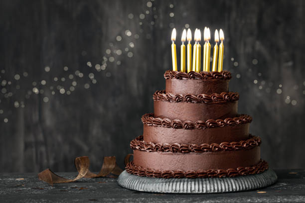 istock Tiered chocolate birthday cake with gold birthday candles 1393290159