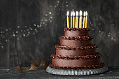 Tiered chocolate birthday cake with gold birthday candles