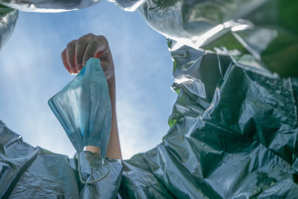 istock A hand throwing away a disposable face mask. 1393303468