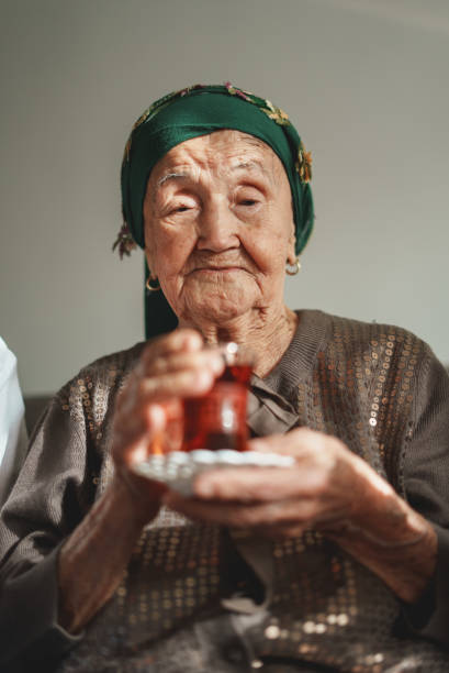 Close up of lovely senior lady looking away and smiling while holding glass cup of hot drink