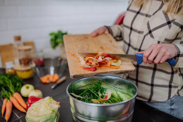 istock Woman throwing vegetable cuttings in a compost bucket in kitchen. 1393304003